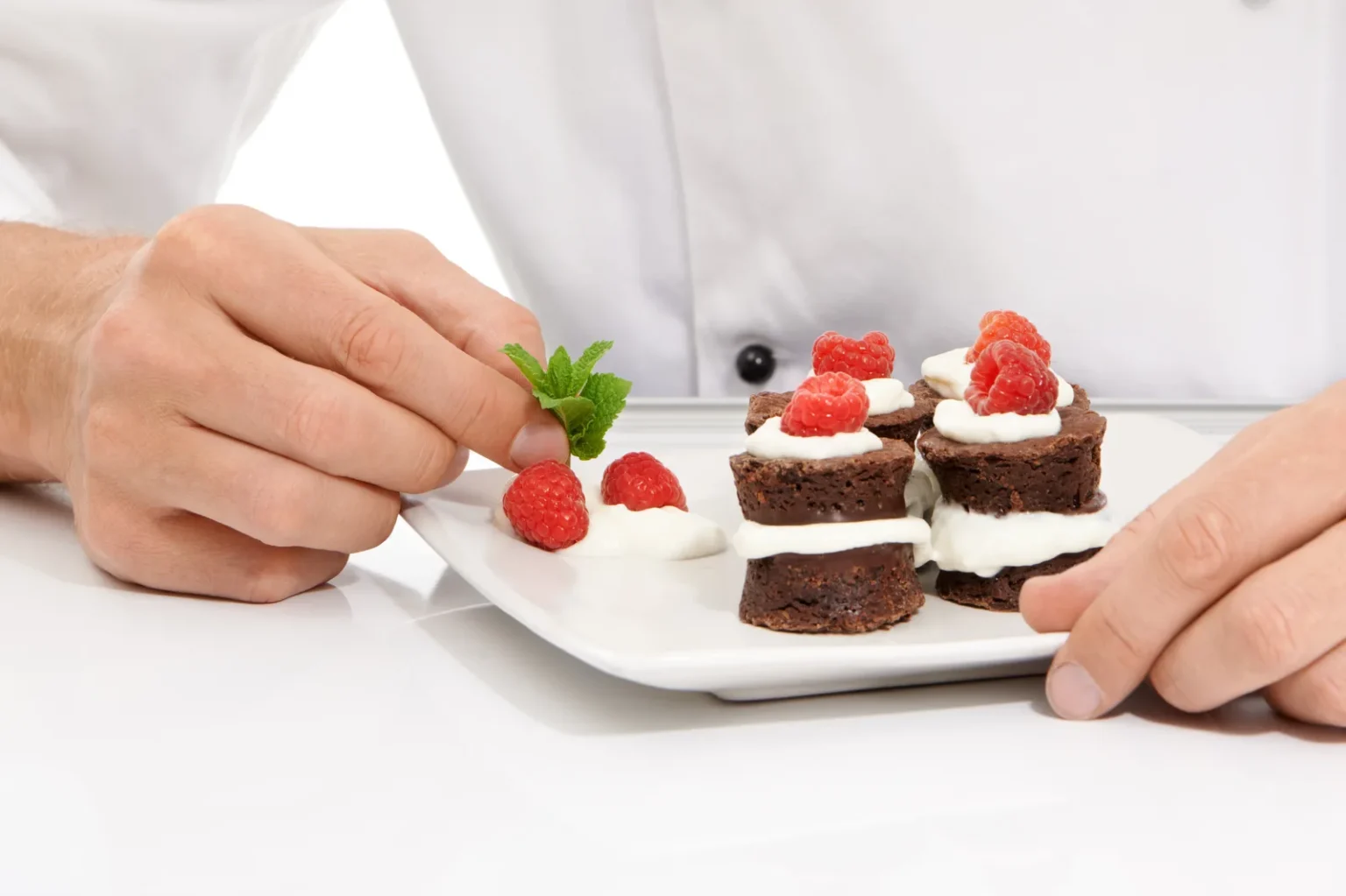 Chef plating raspberry and chocolate desserts as part of a diploma in bakery & confectionery
