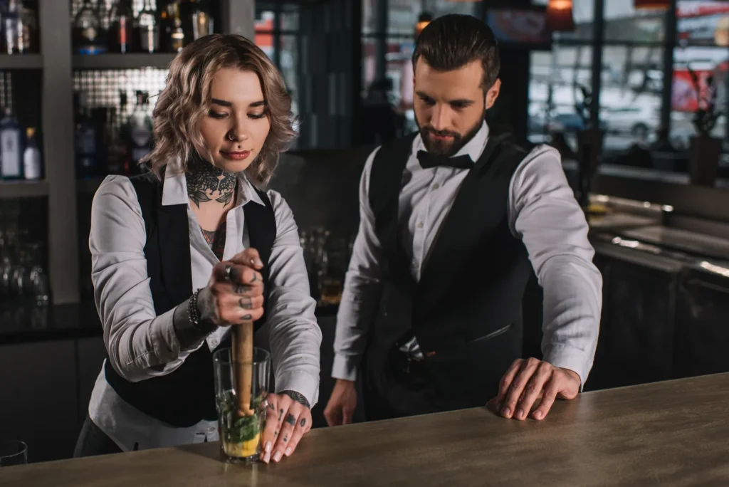 Bartending school: bartenders preparing fresh cocktails at an urban bar