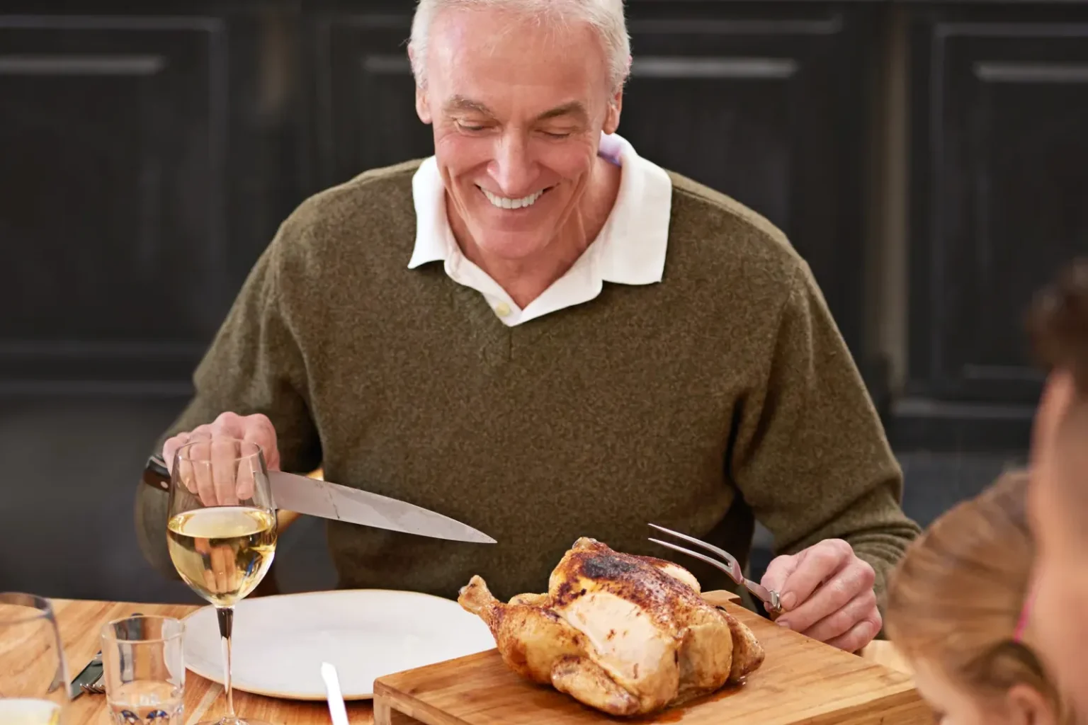 English service: a host carves a roast chicken at a family dinner table