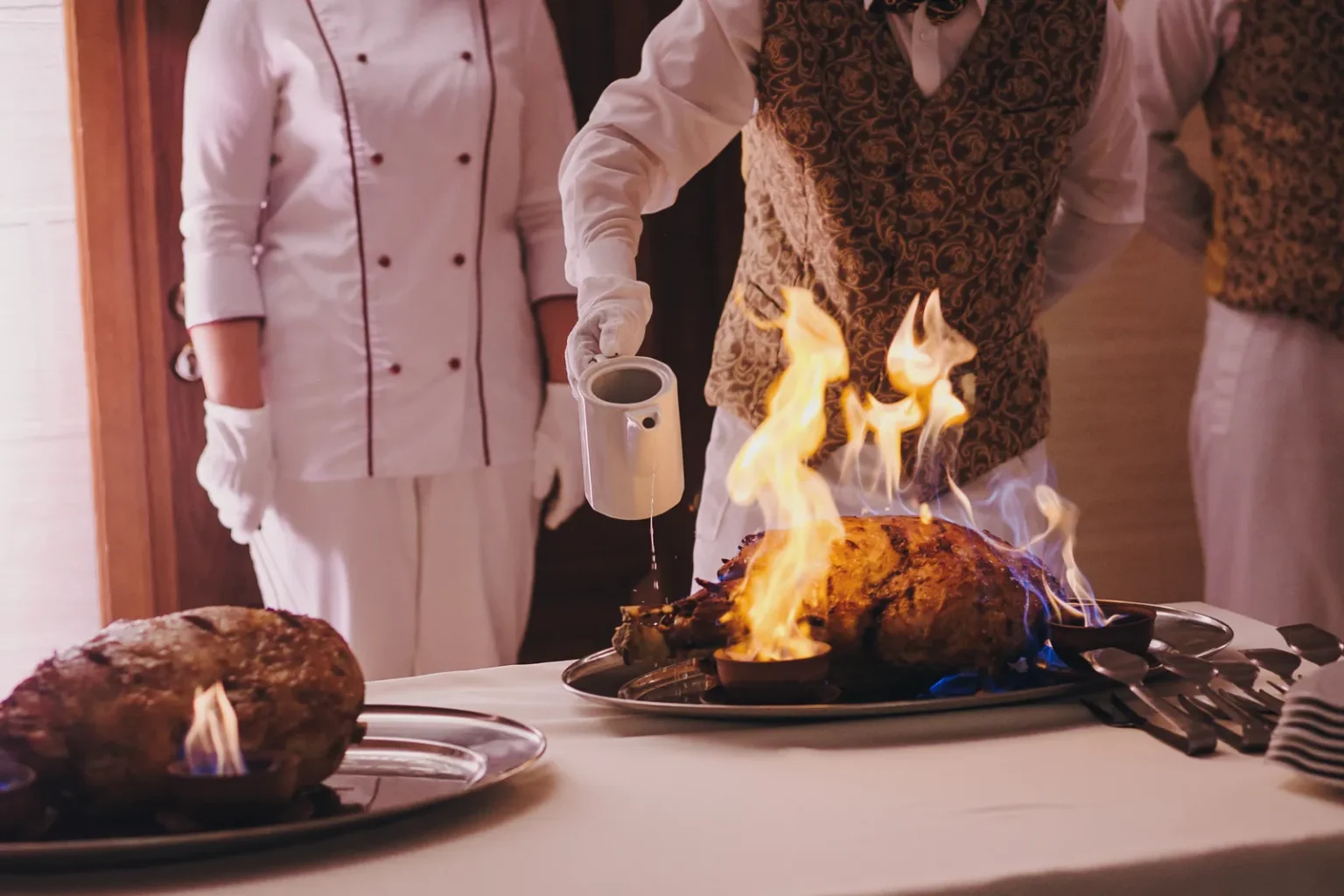 French service: restaurant staff flambe a poultry dish at the table