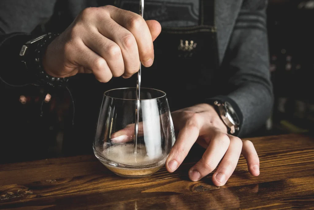 Method of making cocktail: bartender preparing a craft cocktail at the bar