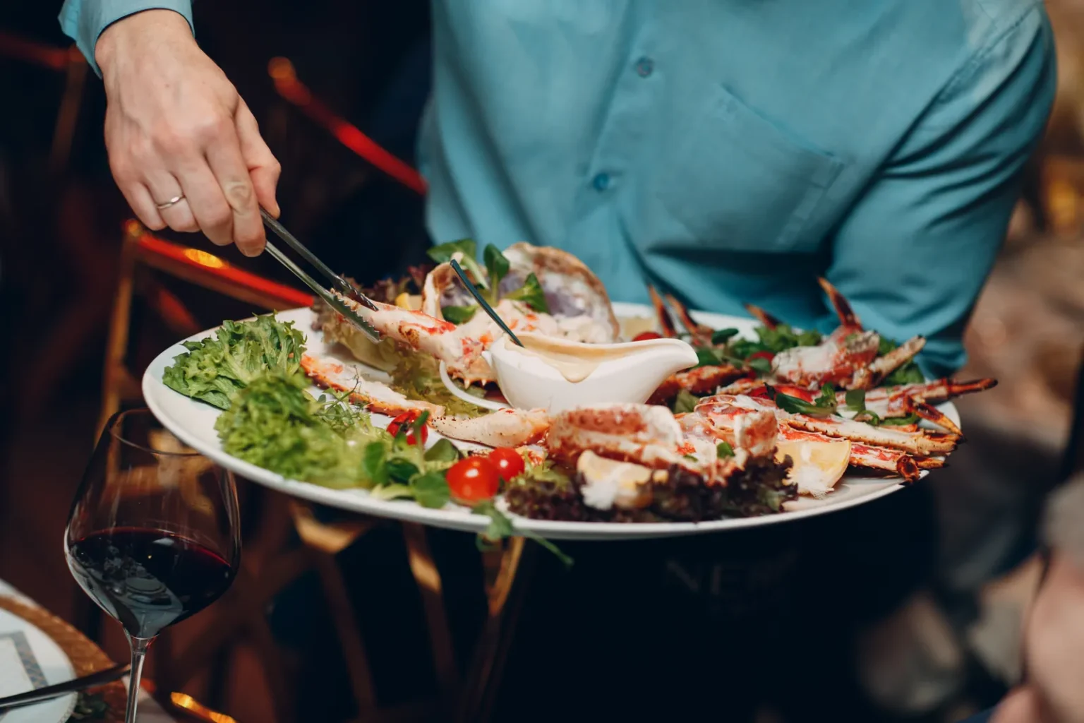 Russian service: a waiter presents a platter of crab at a high-end restaurant table